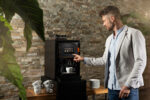 A man tapping on the screen of an Animo OptiMe X coffee machine