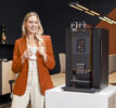 Dame drinkt koffie uit een Animo OptiBean X koffiemachine voor de zakelijke markt