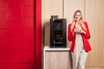 Dame drinkt koffie naast een Animo OptiBean X koffiemachine