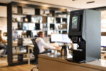 Man achter bureau met op de voorgrond Animo OptiVend koffiemachine voor bedrijven